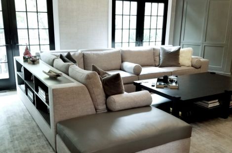 Elegant grey custom upholstered L shaped sectional with bolster pillows and a built in custom bookcase attached to the back of the sectional. \r\nInteriors: Ginger Surasky\r\nUpholstery: Bespoke by Luigi Gentile