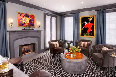 The baltic tufted club chairs in deep charcoal velvet, featuring rolled arms, nailhead trim, and cozy faux-fur pillows for warmth.