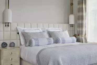 This headboard features a quilted biscuit-tufted design in cream upholstery, creating a tailored, elegant, and contemporary statement.